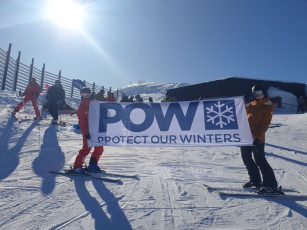 Protect our winters sign held up by two skiers