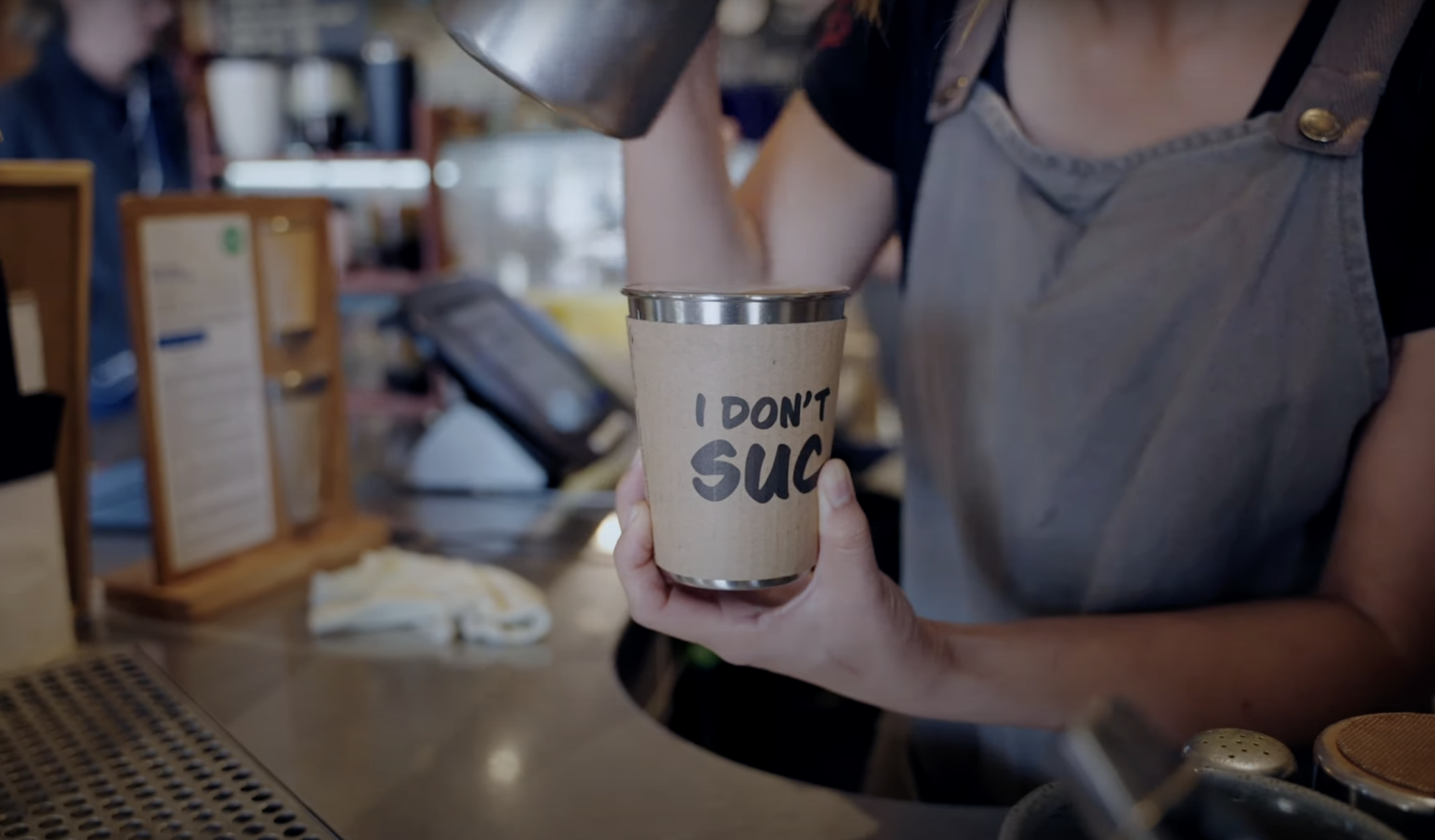 Barista pouring coffee into reusable cup