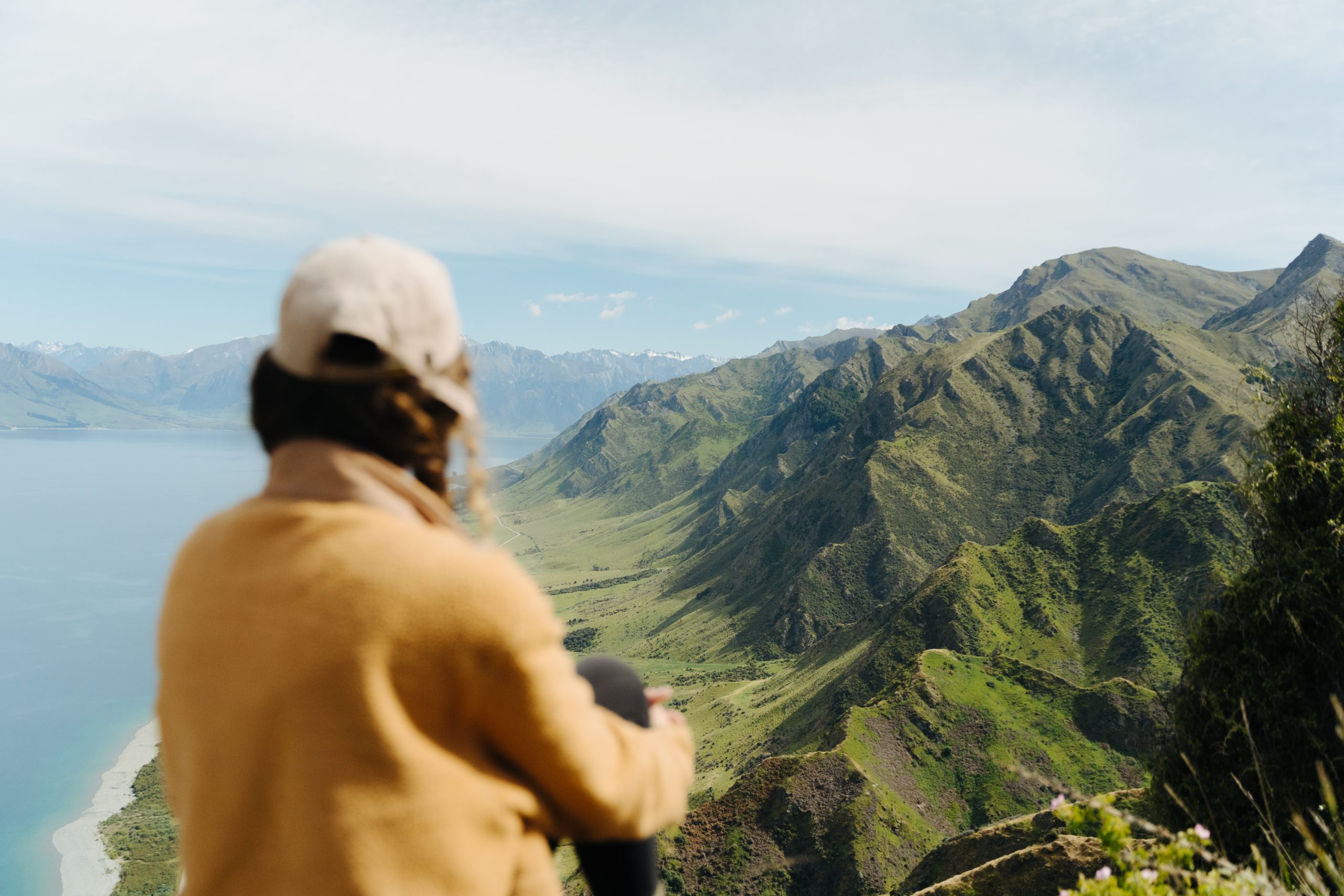 Hiker looks out to view over lake and mountain scene.