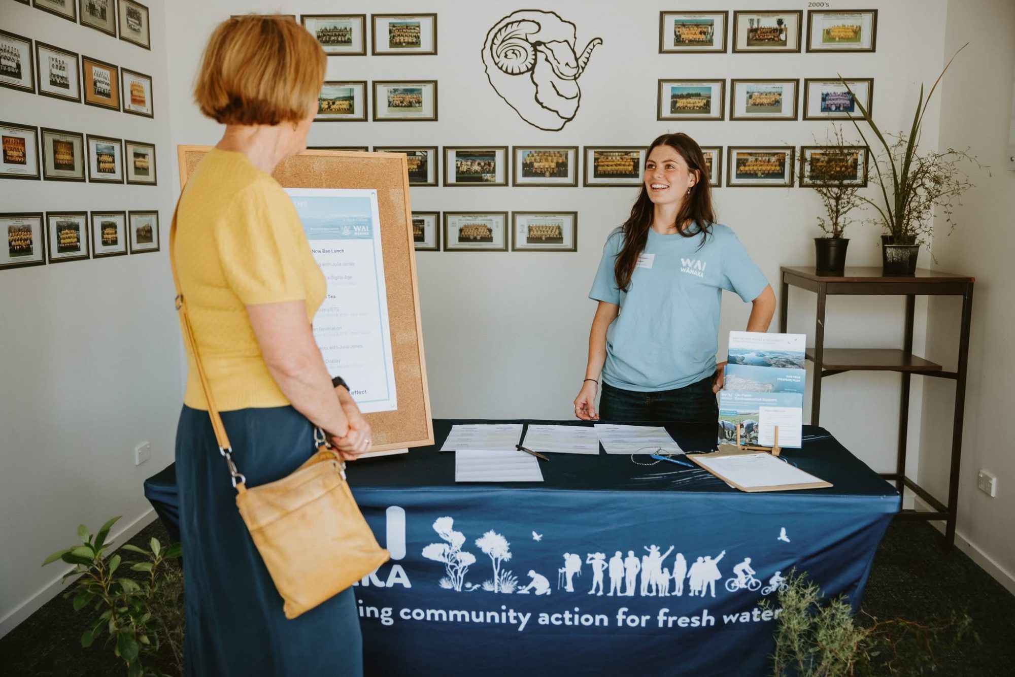 WAI Wānaka team member engaging with a community visitor at an information stand about freshwater initiative
