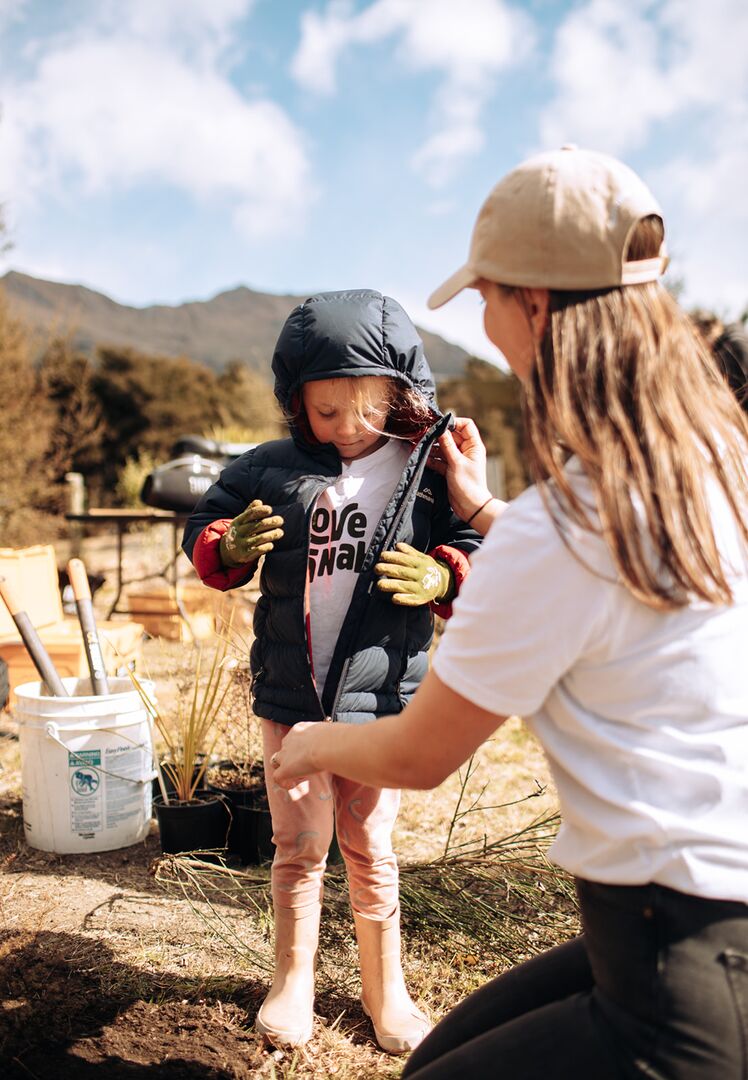 Young volunteer in Love Wanaka shirt learning planting techniques at Te Kākano community conservation day