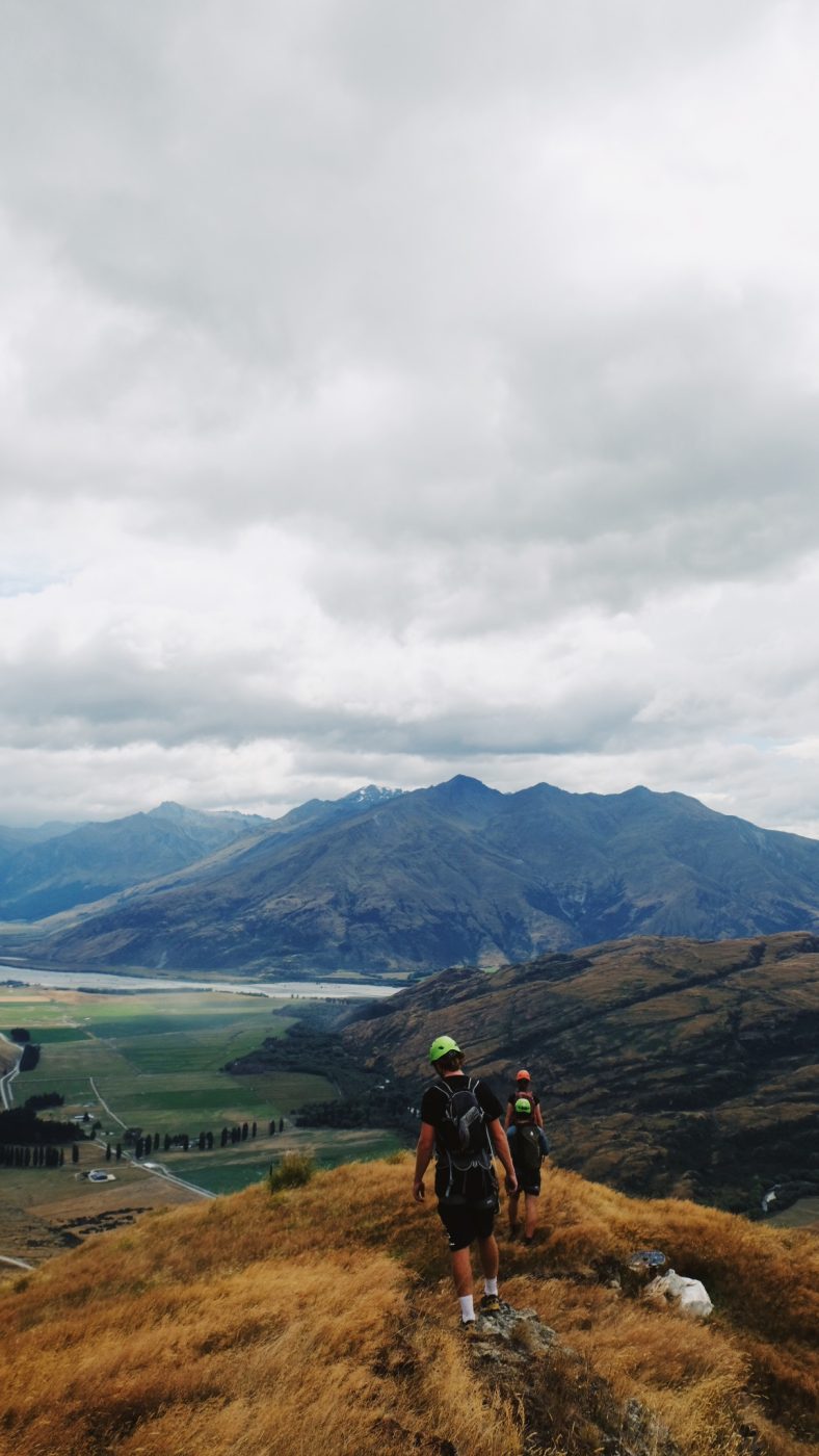 two people standing at the top of the climb at Wildwire, with Glendhu Bay in the background.