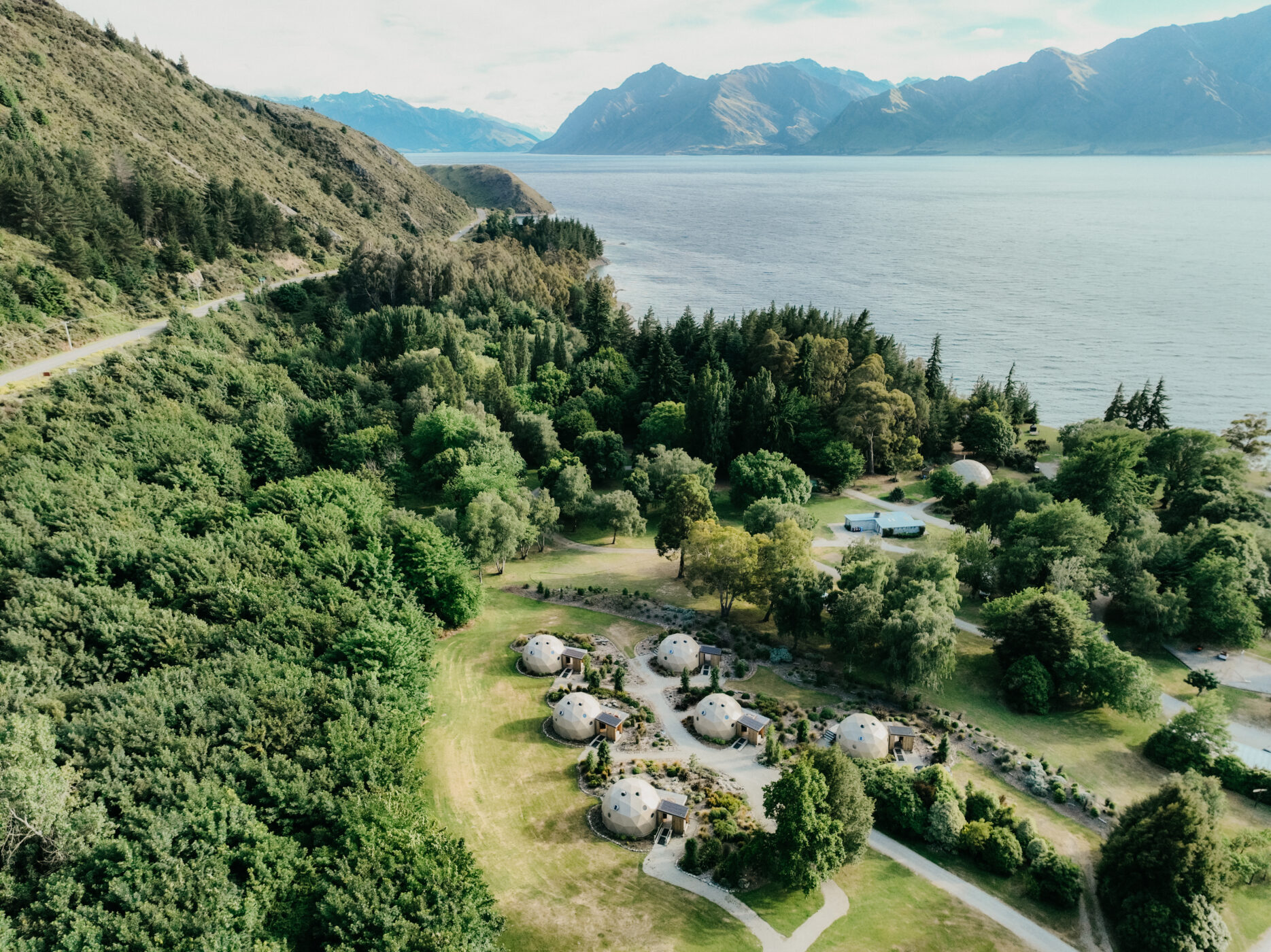 Aerial view of Cross Hill Geodomes with Lake Hāwea and surrounding mountains in background