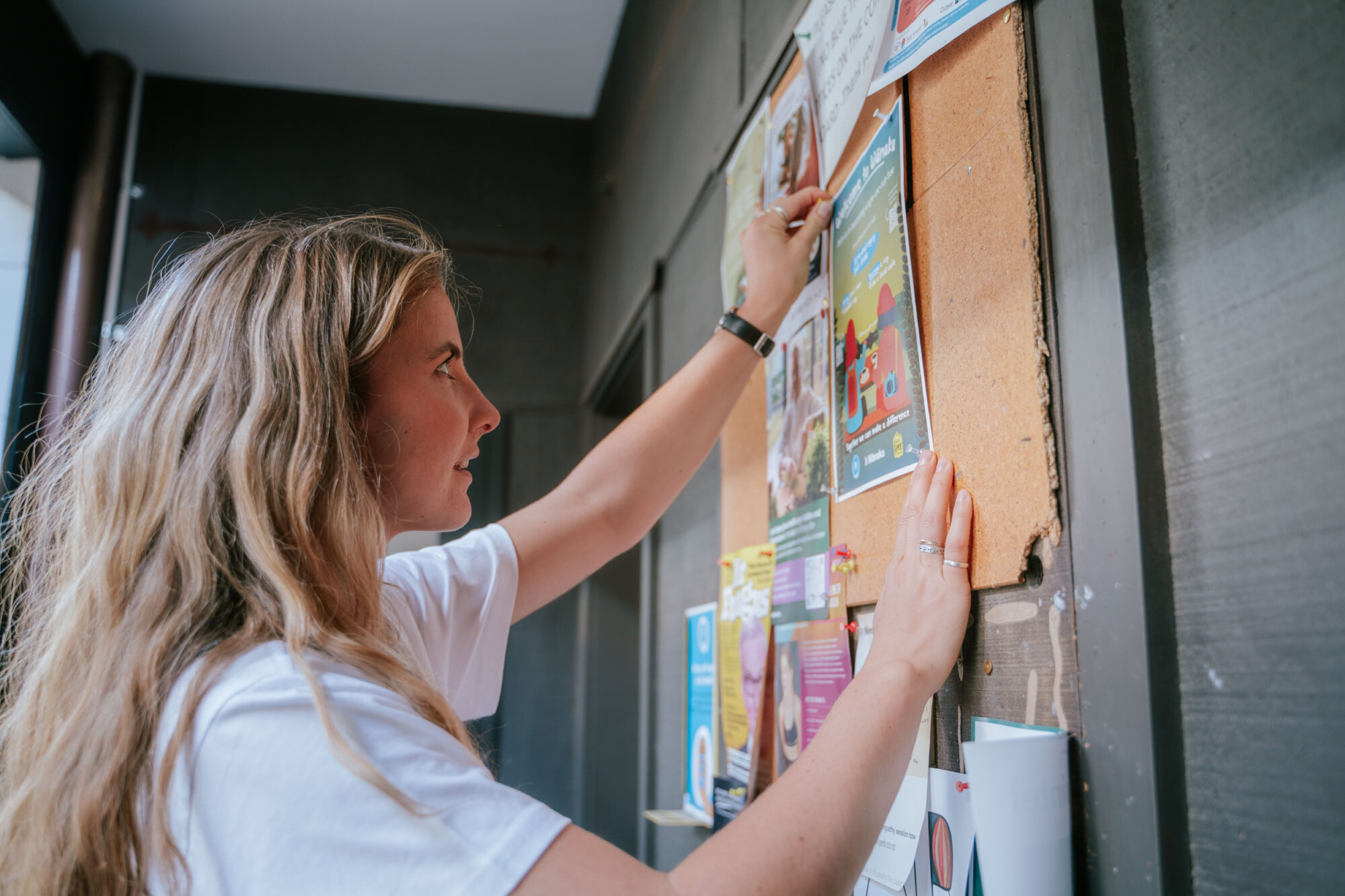 Volunteer sticks poster to pin board